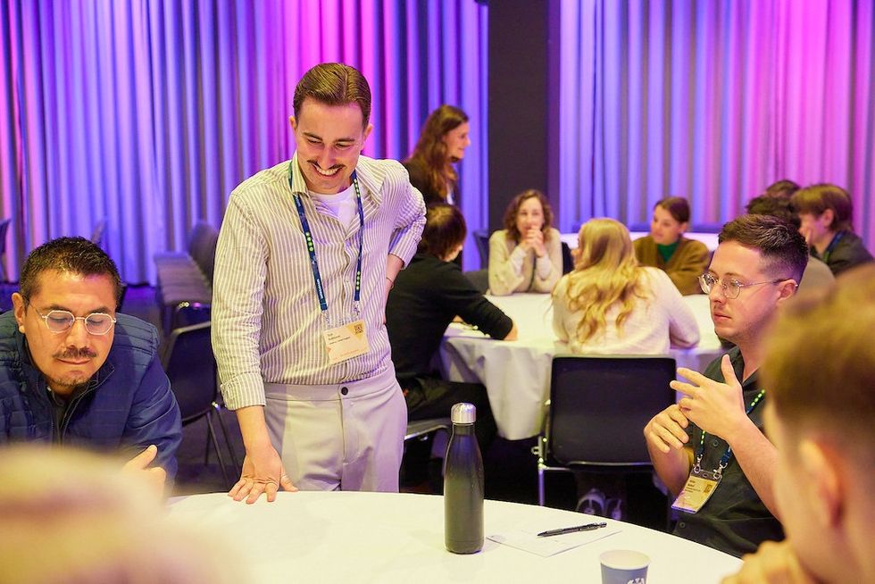 People engaged in a lively discussion around a table, lit by colorful ambient lights.