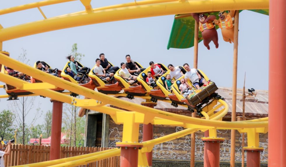 People enjoy a thrilling yellow roller coaster ride at an amusement park, Fantawild Oriental Heritage
