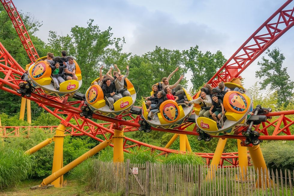 People enjoy a vibrant, twisty roller coaster ride surrounded by lush greenery at Le Pal