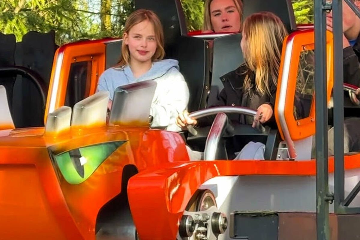 People enjoy an amusement park ride in an orange monster-themed vehicle.