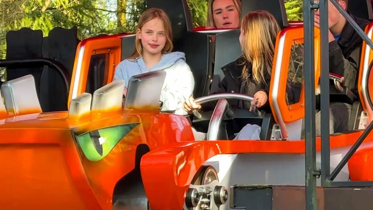 People enjoy an amusement park ride in an orange monster-themed vehicle.