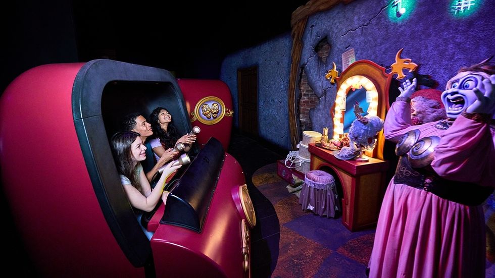 People enjoy the theme park ride, Phantom Theater: Opening Nightmare, with animated scenes in a dark, creepy setting.