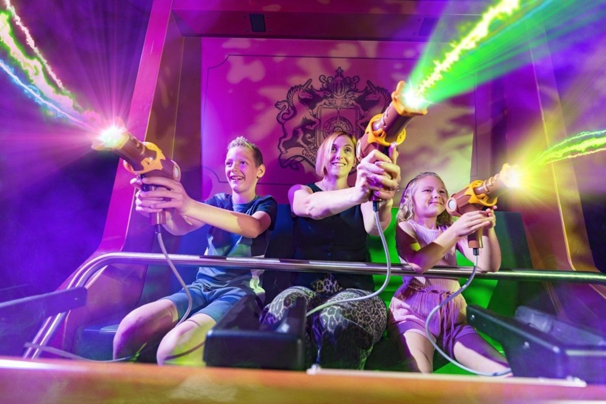 People enjoying a colorful laser tag ride, shooting neon beams, smiling and excited.