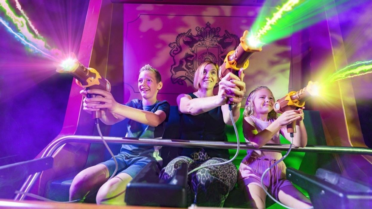 People enjoying a colorful laser tag ride, shooting neon beams, smiling and excited.