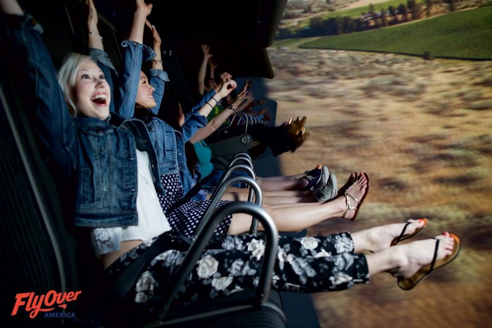 People enjoying a FlyOver America simulation ride with arms raised.