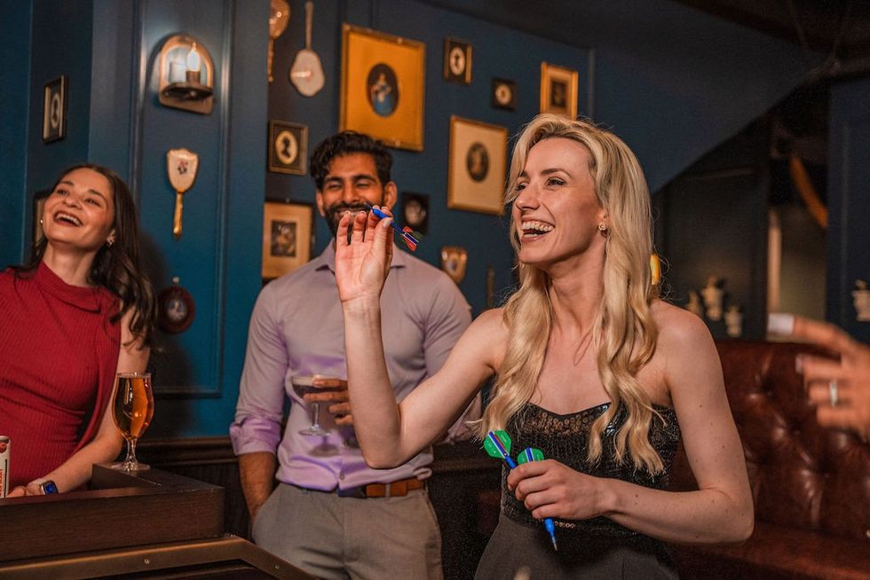 People enjoying a game of darts in a warmly lit bar.