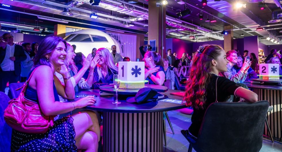 People enjoying a lively event with colorful lights and airplane decor in the background.