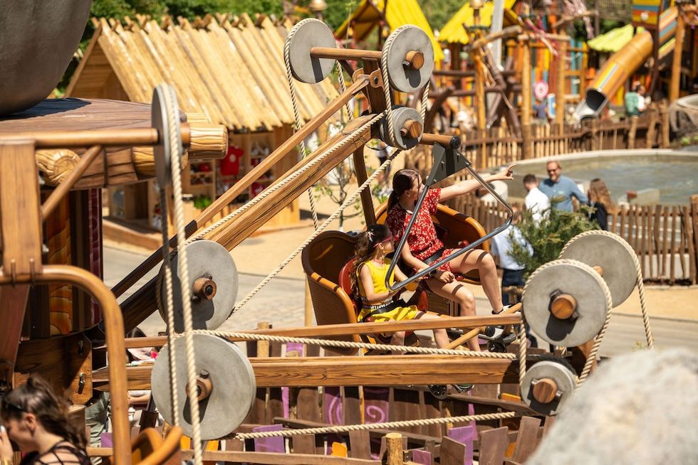People enjoying a mechanical ride in a vibrant amusement park setting.