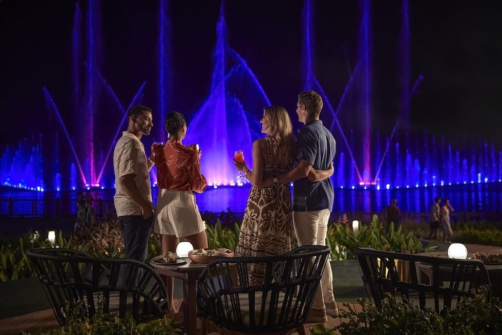 People enjoying a night fountain show with vibrant blue lights.