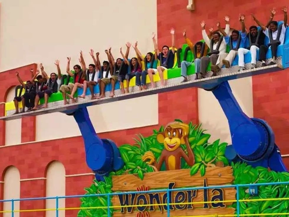 People enjoying a ride with arms raised at an amusement park.
