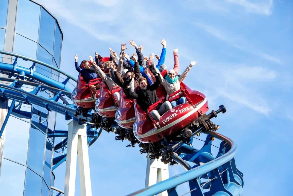 People enjoying a roller coaster ride at Europa Park, hands up in excitement.