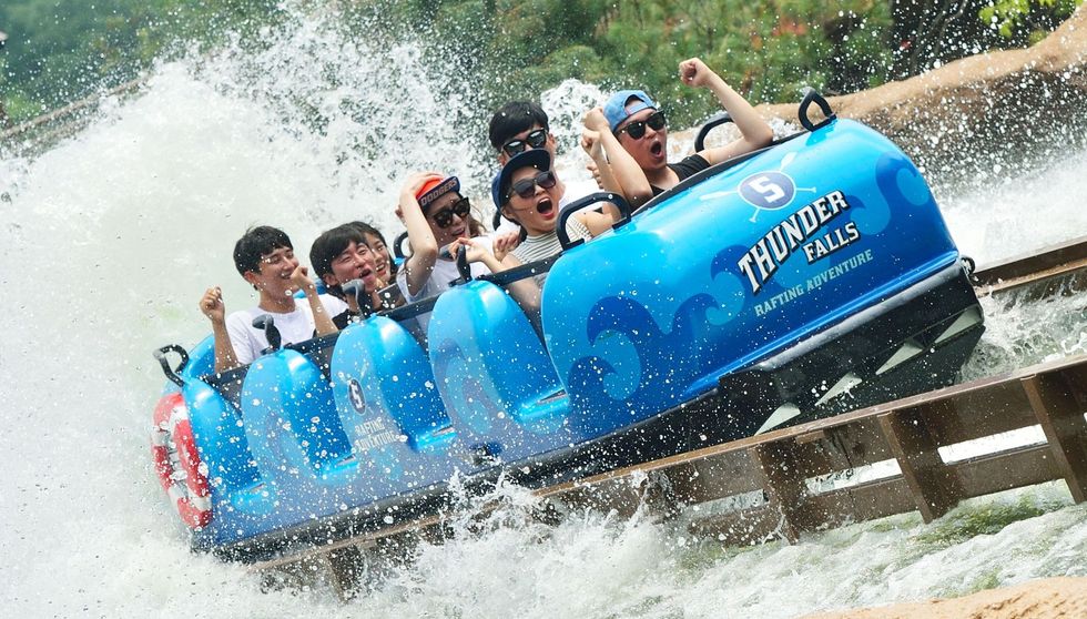 People enjoying a splash on a Thunder Falls rafting ride at an amusement park.