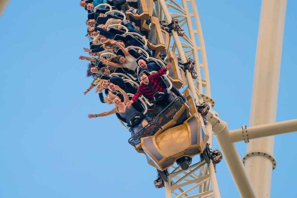 People enjoying a steep descent on a roller coaster, Hyperion, under a clear blue sky at Thorpe Park