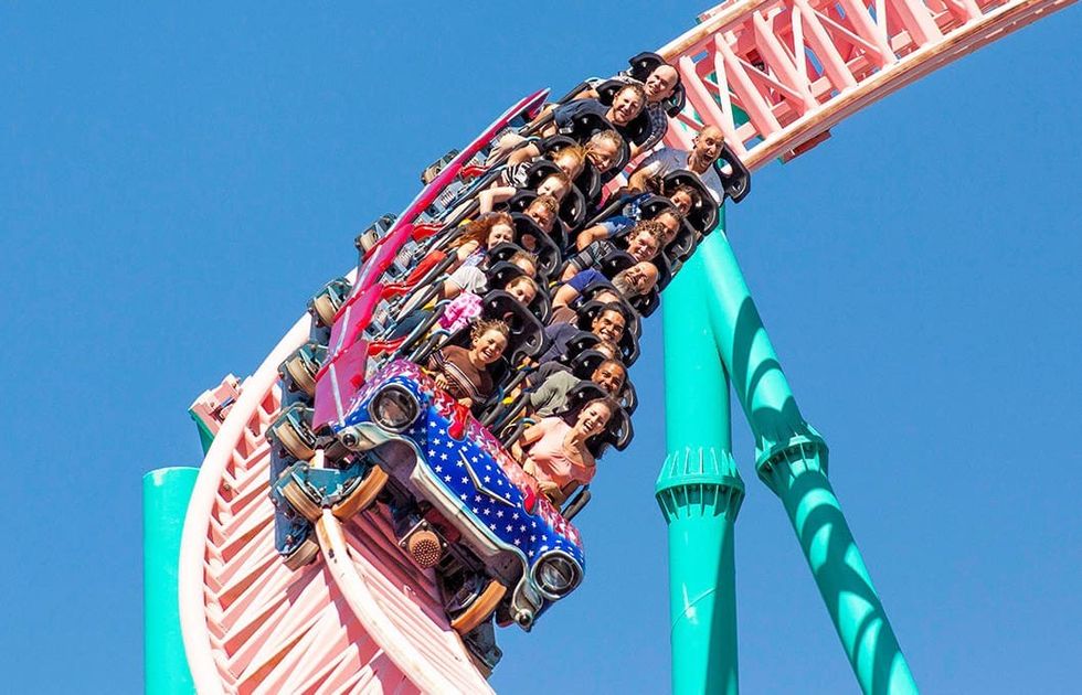People enjoying a steep roller coaster ride under a clear blue sky at Knott's Berry Farm