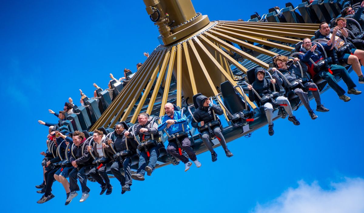 People enjoying a swing ride against a blue sky.