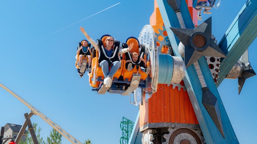 People enjoying a thrilling amusement park ride under a clear blue sky.