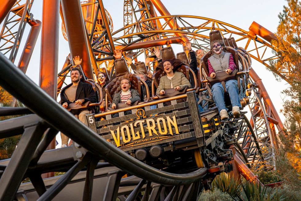 People enjoying a thrilling ride on the Voltron roller coaster at sunset.