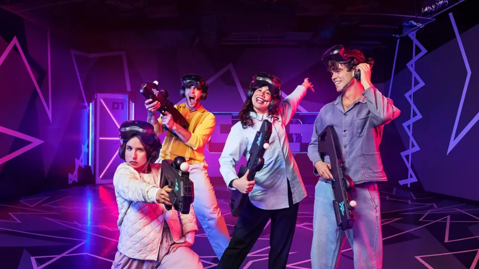 People enjoying a VR experience, holding controllers, with colorful geometric background.