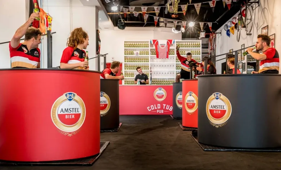 People enjoying drinks in Amstel-branded cold tubs at a pub.