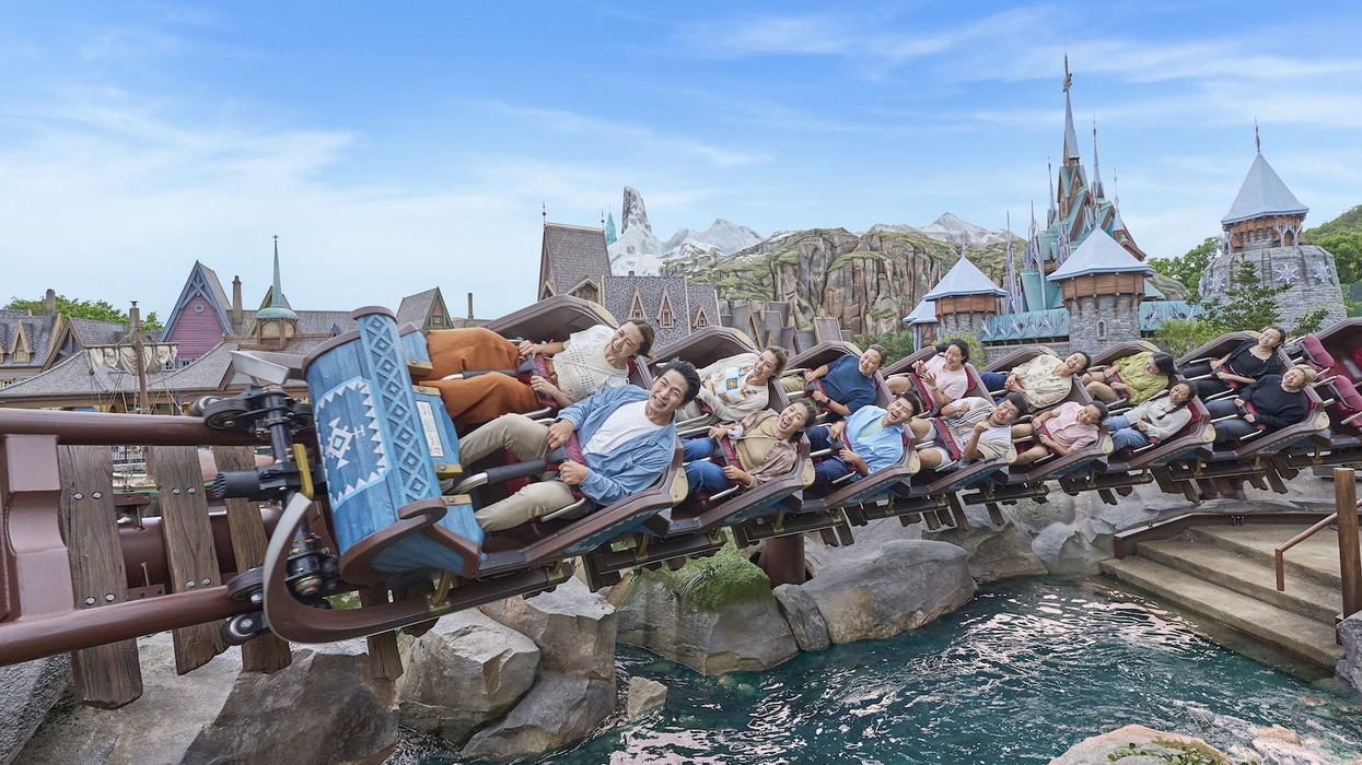 People enjoying Frozen-themed roller coaster ride in Hong Kong Disneyland with castle in the background.