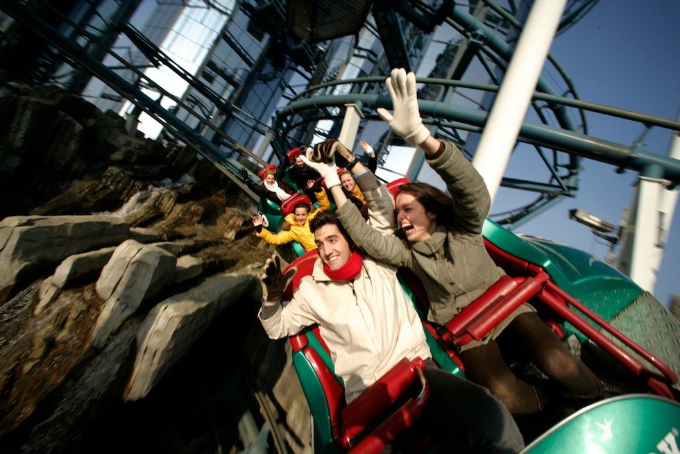 People enjoying outdoor section of Euro-Mir roller coaster ride, waving and smiling.