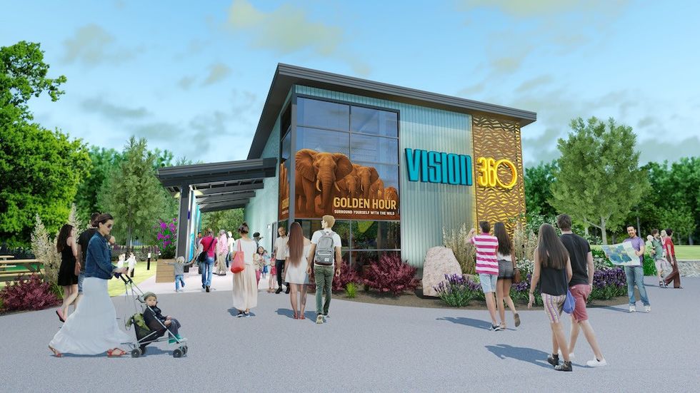 People entering a modern building with large windows and nature-themed graphics.