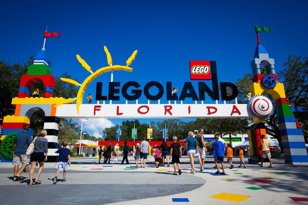 People entering colorful LEGOLAND Florida entrance under a sunny sky.