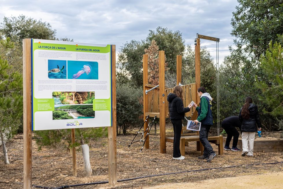 People examining an educational water display in an outdoor park setting at PortAventura World