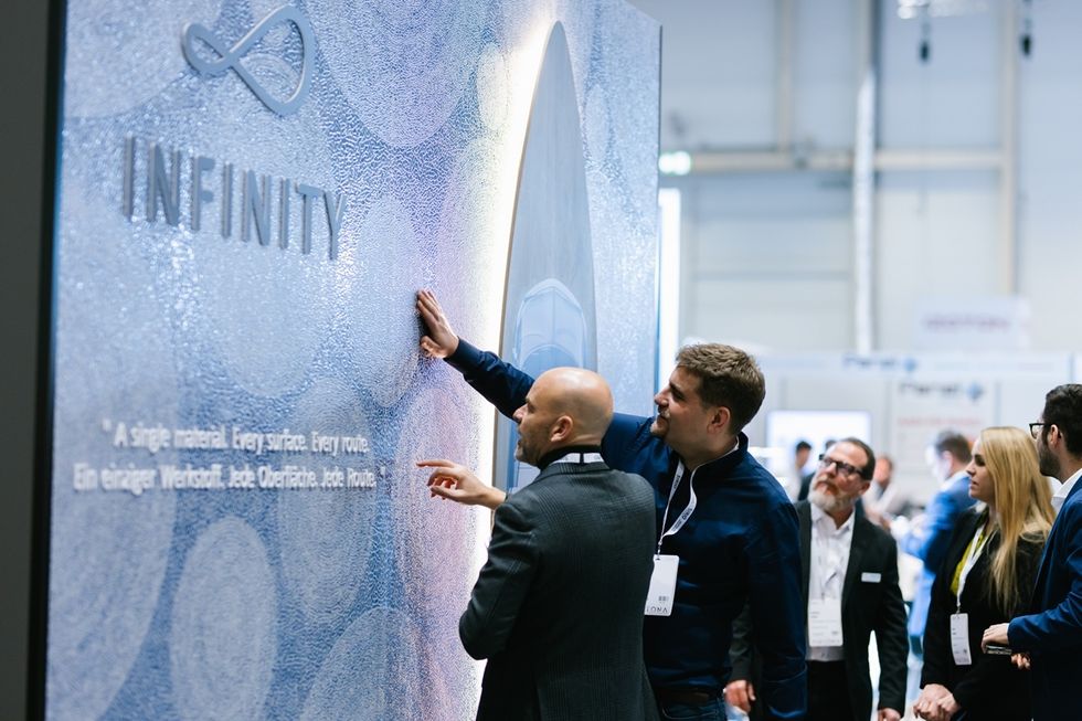 People examining an "INFINITY" display at an indoor event.