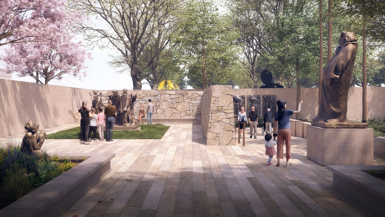People explore a sculpture garden with statues and stone walls under leafy trees.