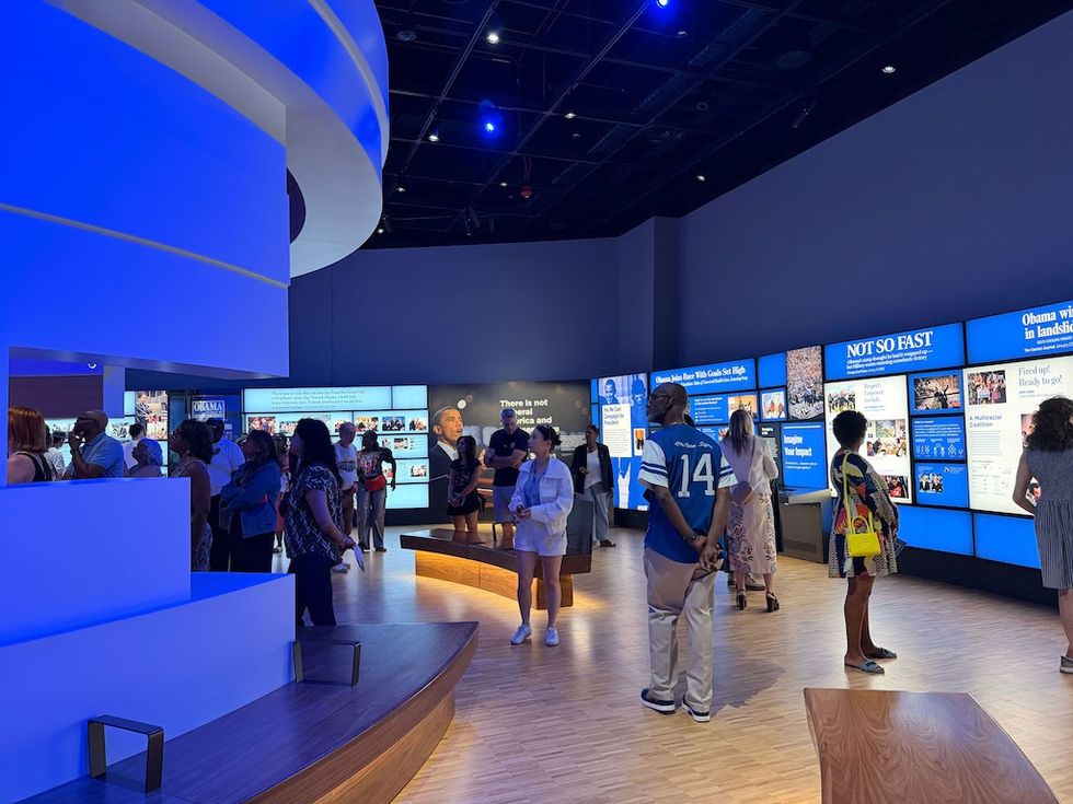 People explore an exhibit with blue-lit information panels and displays in a modern museum.