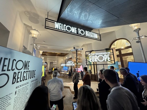 People exploring a Belgium-themed exhibition space with welcoming signs.