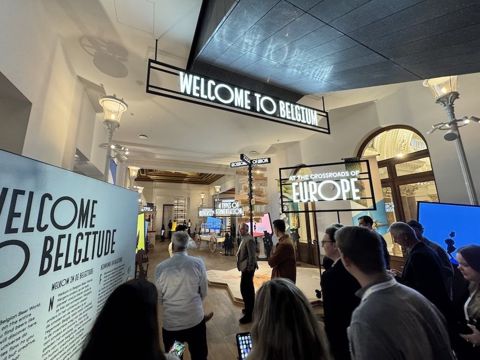 People exploring a Belgium-themed exhibition space with welcoming signs.