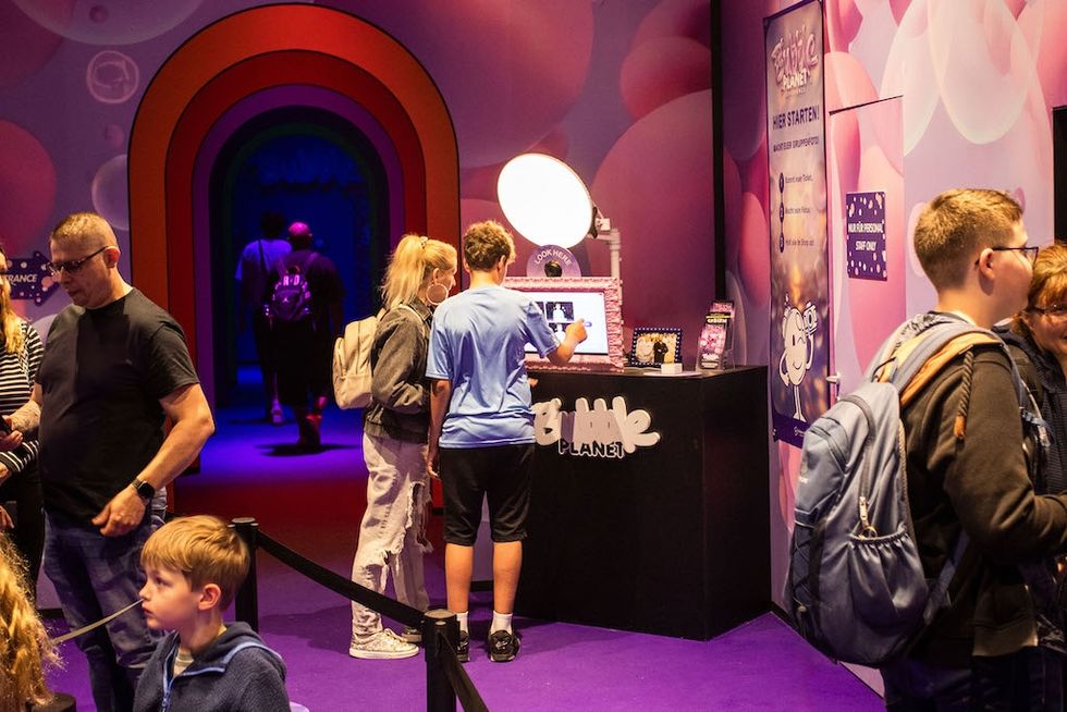 People exploring a colorful photo kiosk at Bubble Planet.