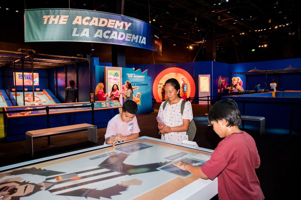People exploring interactive exhibits at "The Academy" indoor event.