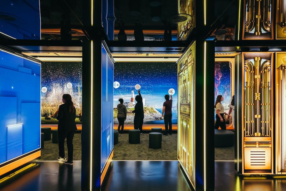 People exploring vibrant, futuristic interactive exhibits in a tech museum.