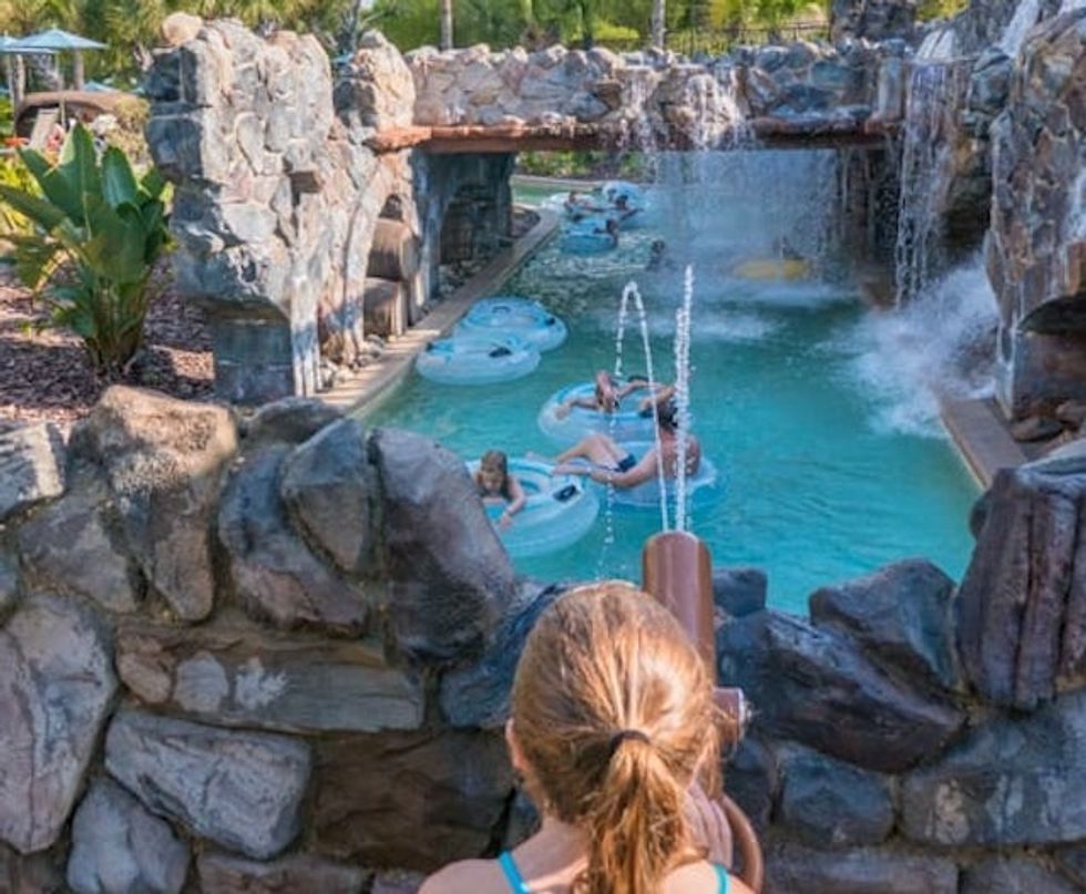 People floating on a lazy river surrounded by rocky waterfalls.