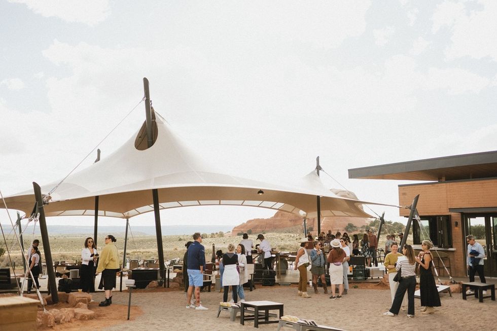 People gather under a large canopy in a desert landscape setting.