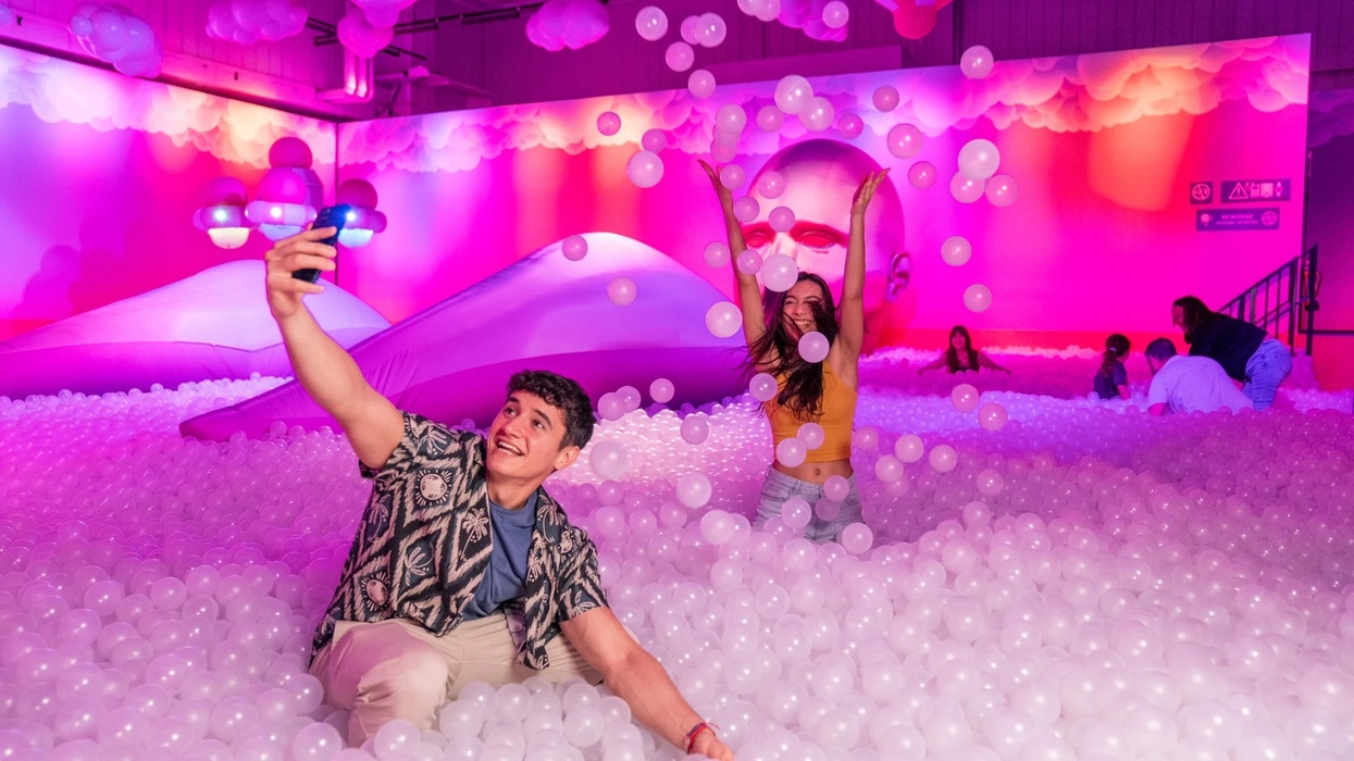 People having fun in a colorful ball pit, taking selfies and playing with white plastic balls at Bubble Planet