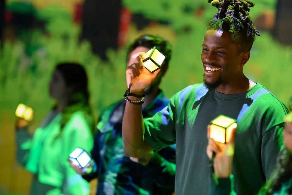 People holding glowing cubes against a vibrant, green-lit background in Minecraft Experience: Villager Rescue