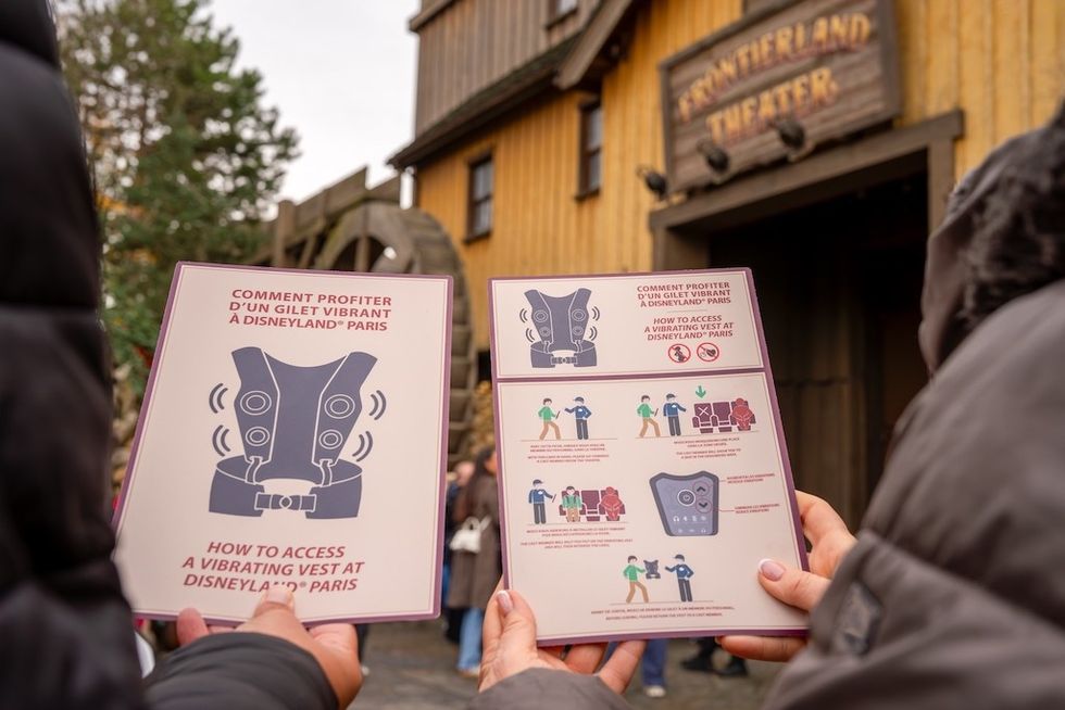 People holding instruction cards for vibrating vests at Disneyland Paris.