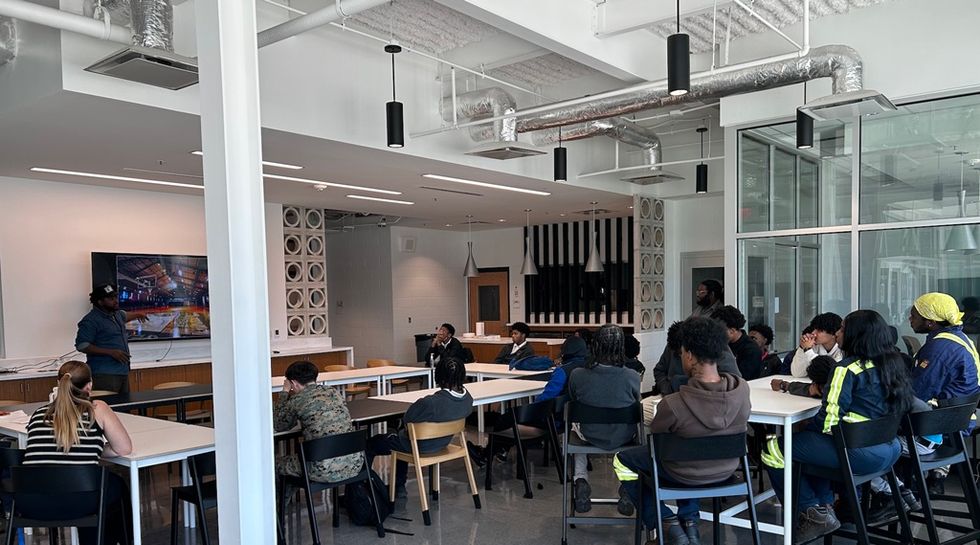 People in a modern classroom attending a presentation with a screen.