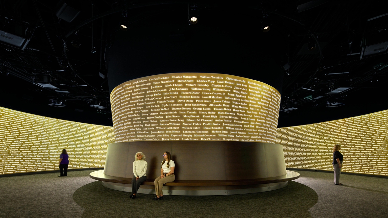 People in a room with walls covered in illuminated, circular lists of names - Redglass Pictures