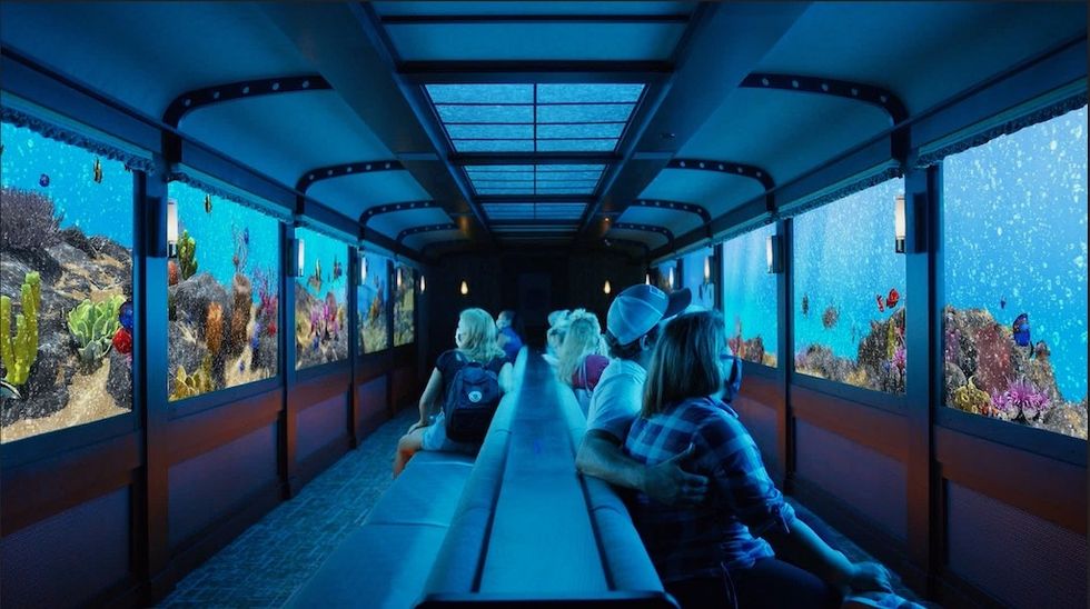 People in an aquarium-themed train journey at St Louis Aquarium, with large viewing windows showing underwater scenes.