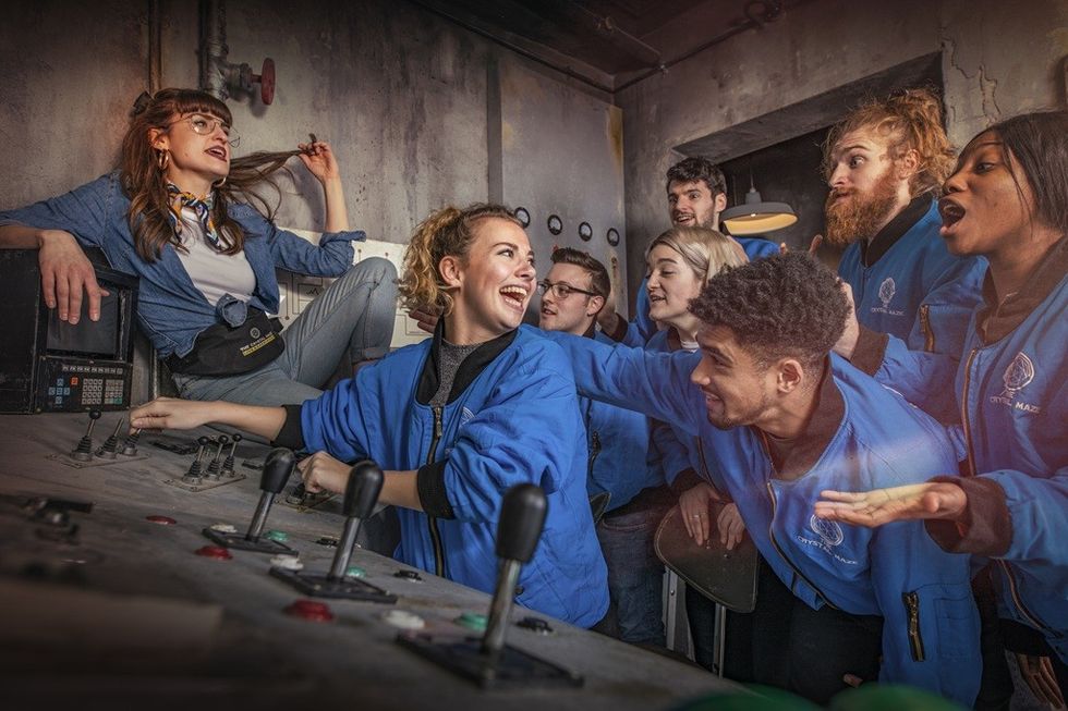 People in blue jackets cheering and interacting in a control room.