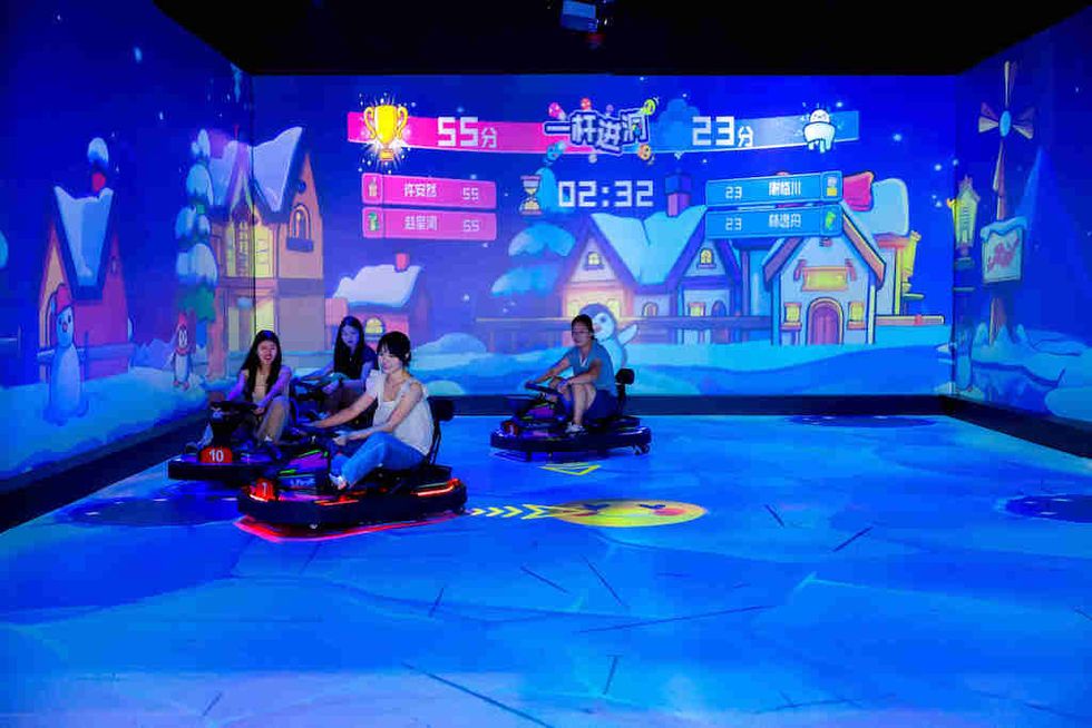 People in bumper cars enjoy an animated snowy village arcade game.