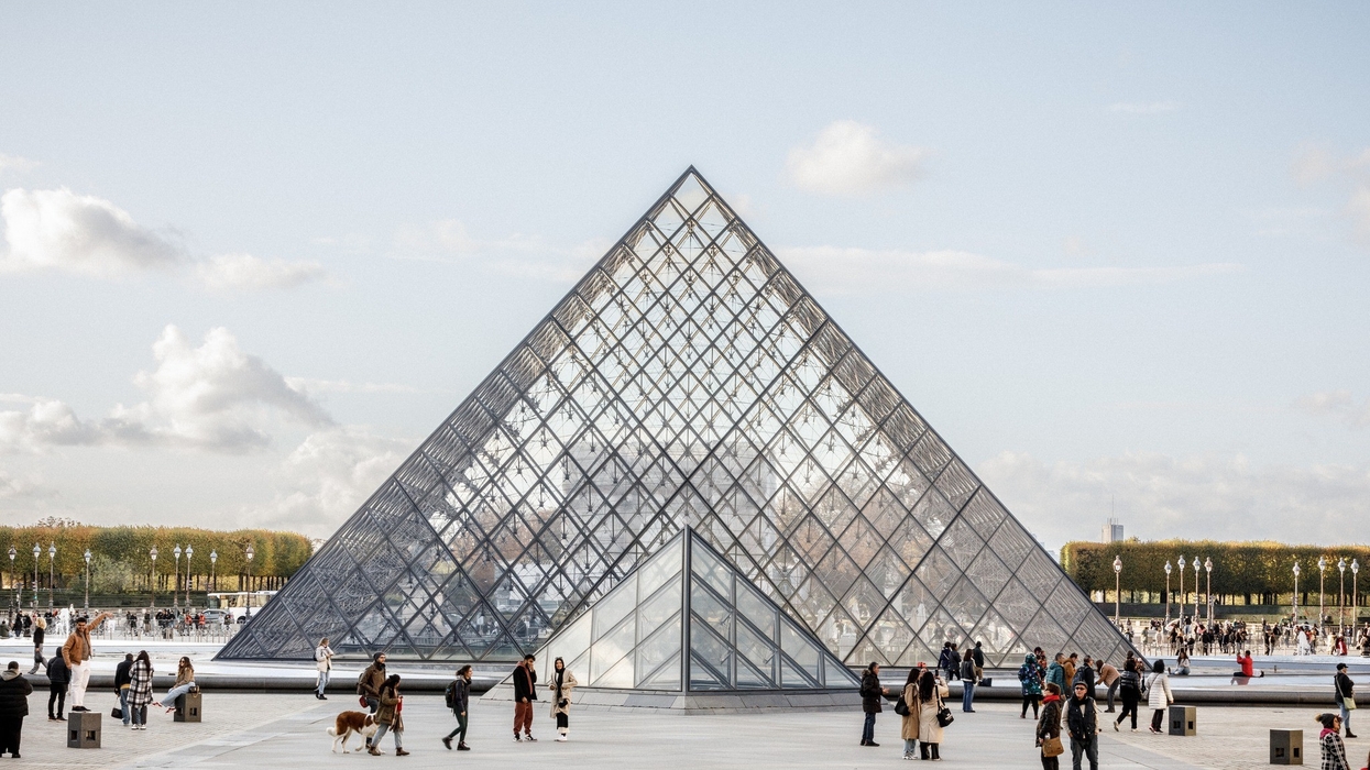 People in front of the glass pyramid at the Louvre Museum, Paris.
