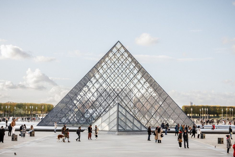 People in front of the glass pyramid at the Louvre Museum, Paris.