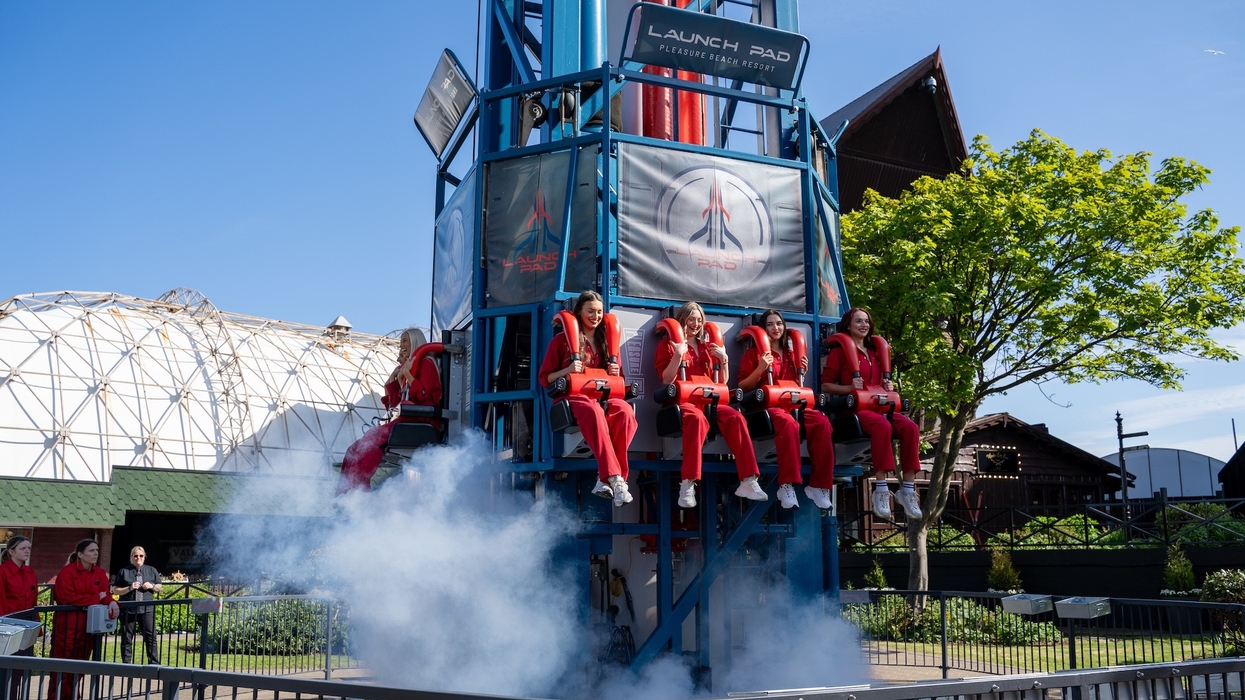 People in red suits on Pleasure Beach's Launch Pad ride, with smoke and blue skies.