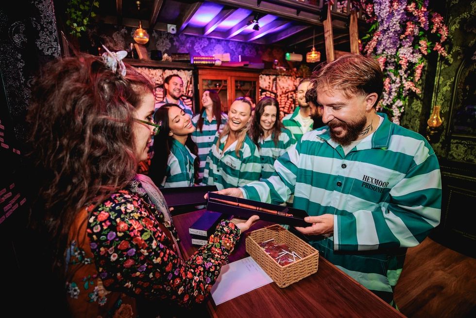 People in striped costumes enjoy an interactive game experience in a vibrant room.